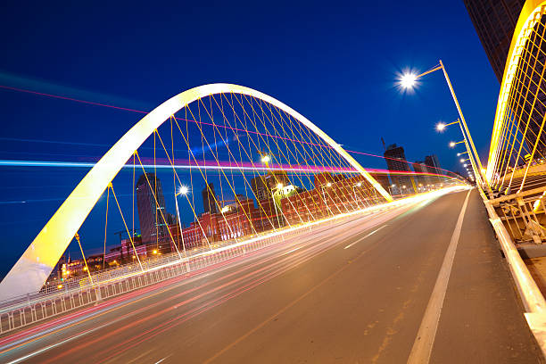 istock Arc bridge girder highway car light trails city night landscape 491728589