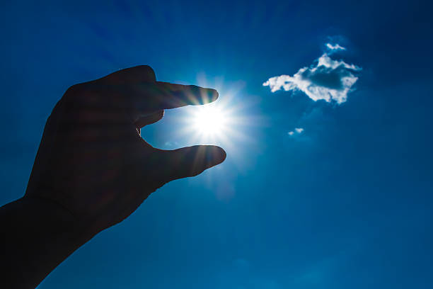 istock Silhouette of Hand picking sun at blue sky and cloud 491731354