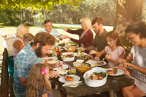 Family enjoying barbecue at outdoors Family having barbecue meal at paved back yard. snag tree stock pictures, royalty-free photos & images