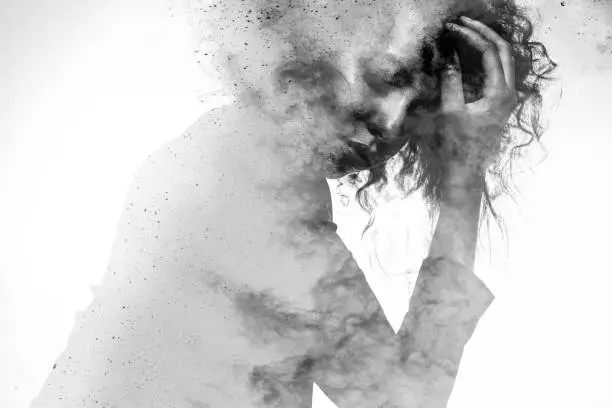 Subtle woman's form in an unhappy pose double exposed with a monochromatic paint splatter photographic effect