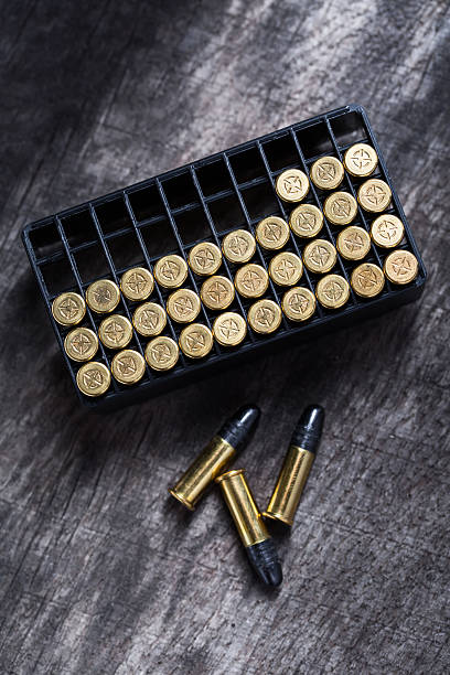 Scattering of small caliber cartridges on a wooden background stock photo