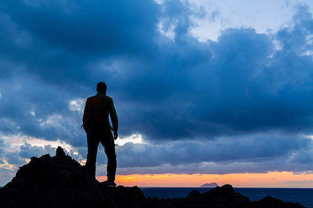 Hiking or trail running accomplish silhouette hiker backpacker, man and success in inspirational sunset landscape. Fitness and healthy lifestyle outdoors in summer nature on Crete, Greece.