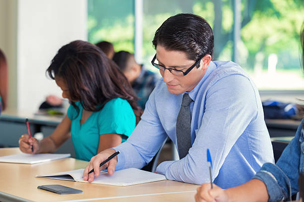 jeune homme prendre des notes en classe de collège moderne en configuration salle de classe - exam business caucasian board room photos et images de collection