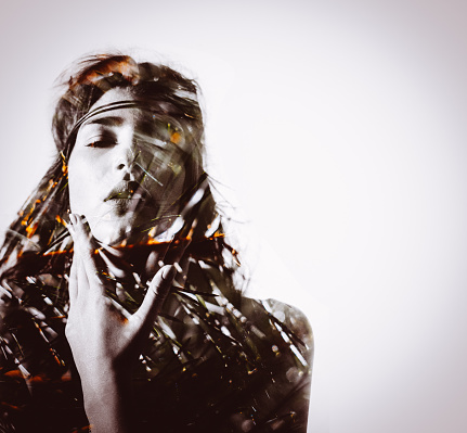 Multiple exposure style image of a tribal looking woman's image overlaid with an image of palm leaves giving it a wild feeling with a sense of movement