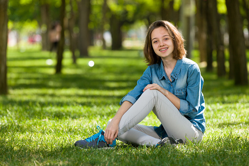 Happy teenage girl string on grass.