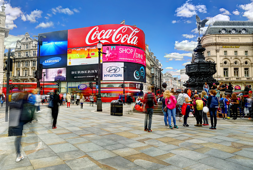London, United Kingdom - August 31st, 2015: HDR long exposure in the afternoon in Piccadilly Circus by the Eros statue with tourists standing around and a bus going past. 
