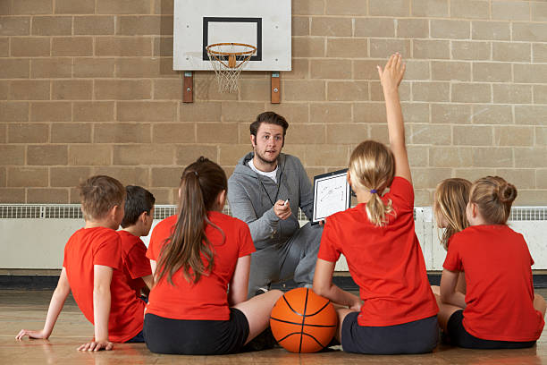 Coach Giving Team Talk To Elementary School Basketball Team Coach Giving Team Talk To Elementary School Basketball Team physical education stock pictures, royalty-free photos & images