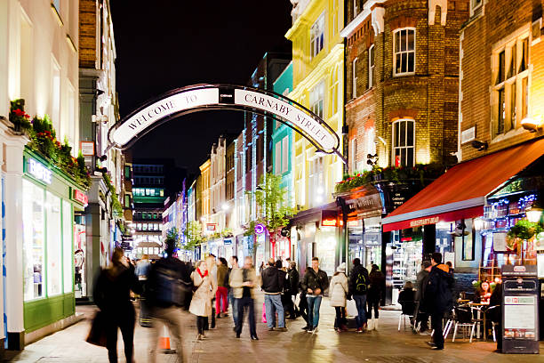 London, England - November 3, 2013: Carnaby street is a shopping street of London, located in Soho. People walking on the street and sitting at the pub's tables.