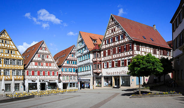 Herrenberg, Germany - May 11, 2014: The central square called Marktplatz (market square) in the city of Herrenberg, Baden-Wuerttemberg, Germany. Timbered houses which are typical for this region. In the houses cafes and shops. Outdoor tables and chairs of the cafe on the square. No person present on this image.