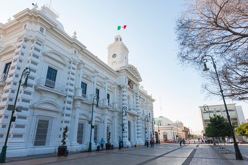 Hermosillo, Mexico - October 21, 2011: Downtown Hermosillo, view of the government palace, located in Plaza Zaragoza in front of the city's cathedral, early in the morning, with some passersby in the street.