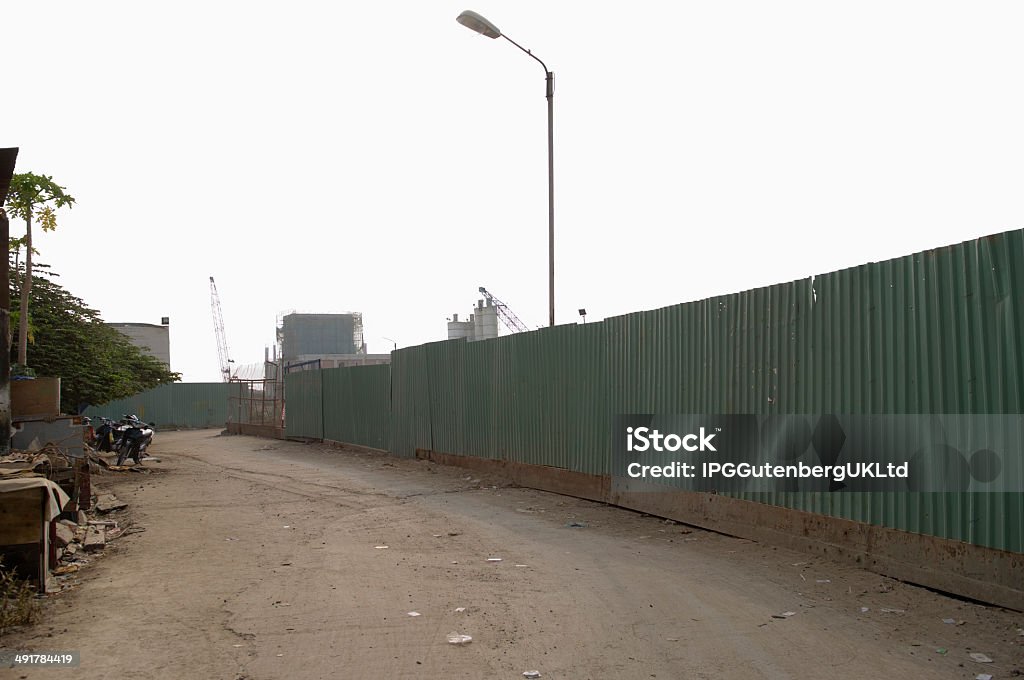 Dirt Road Along Enclosed Corrugated Steel Fence Business Finance and Industry Stock Photo