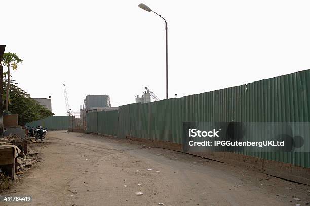 Dirt Road Along Enclosed Corrugated Steel Fence Stock Photo - Download Image Now - Business Finance and Industry, City, City Life