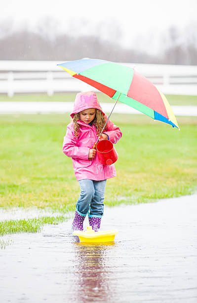 istock Young Girl With Umbrella in Rain Puddle 491786569