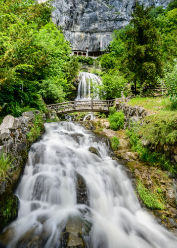 Waterfalls flow beneath the monastery located on the side of a cliff near the entrance of St. Beatus Caves near Lake Thun, Switzerland