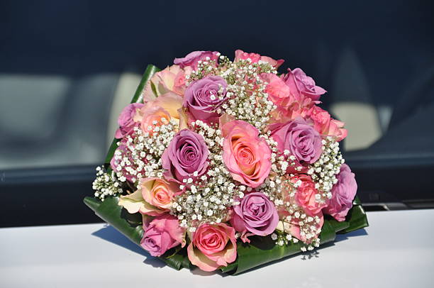 Beautiful bridal bouquet displayed on a hood of a white car. 