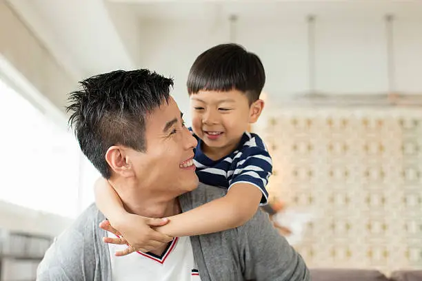 Portrait of a young Chinese father playing with his son.