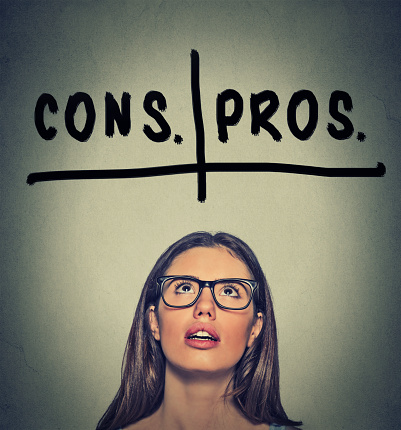 pros and cons, for and against argument concept. Young business woman with glasses looking up deciding isolated on gray wall background. Face expression, emotion, feeling, perception, vision, decision