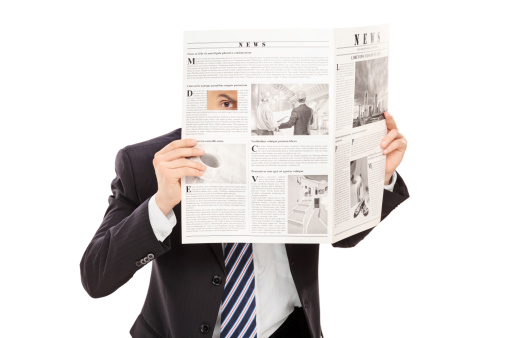 Sneaky boss peeking through a hole in newspaper isolated on white background
