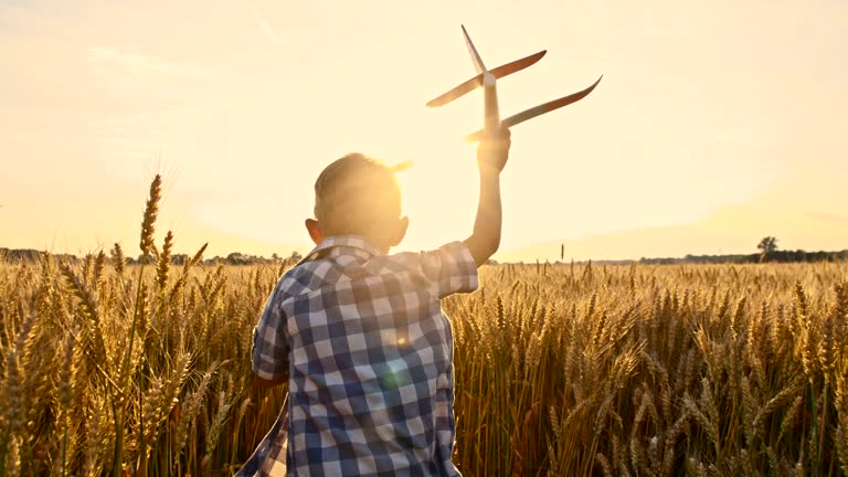 SLO MO Boy throwing airplane toy in wheat field