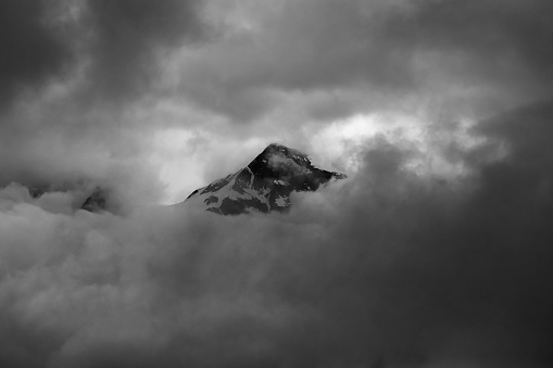 Minimalistic monochrome image of mountain peak shrouded in clouds