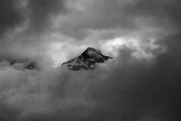 Photo of Minimalistic monochrome image of mountain peak shrouded in clouds