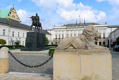 Warsaw, Poland - September 16, 2015: Sculpture of a lion and statue of Prince Jozef Poniatowski in front of the Polish Presidential Palace by sunny day. Palace is the seat of the Polish president.