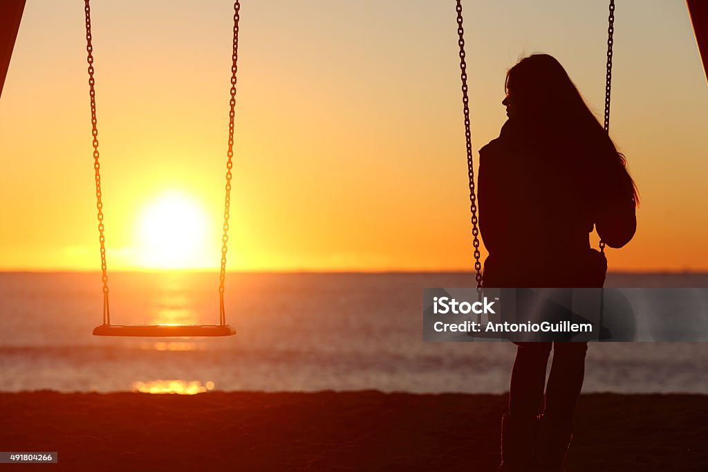 Single woman alone swinging on the beach Single woman alone swinging on the beach and looking the other seat missing a boyfriend Grief Stock Photo