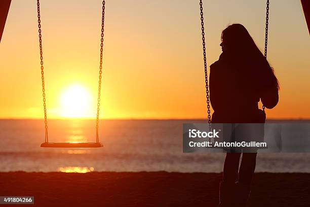Single Woman Alone Swinging On The Beach Stock Photo - Download Image Now - Grief, Loneliness, Child