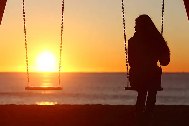 Photo of Single woman alone swinging on the beach