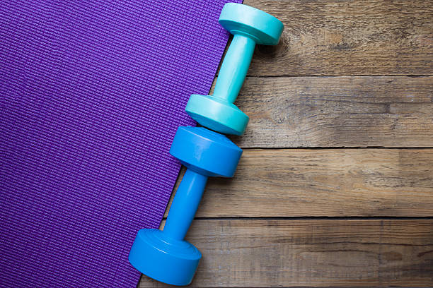 istock dumbbells and yoga mat on wood table 491804770