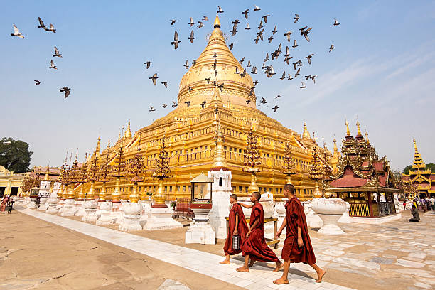 View of Shwezigon Pagoda in Bagan, Myanmar Bagan, Myanmar - March 15, 2014: Novice Buddhist monks walking around the sacred Shwezigon Paya, one of Myanmar's most revered pagodas, in Nyaung U, Bagan, Myanmar (Burma). yangon photos stock pictures, royalty-free photos & images