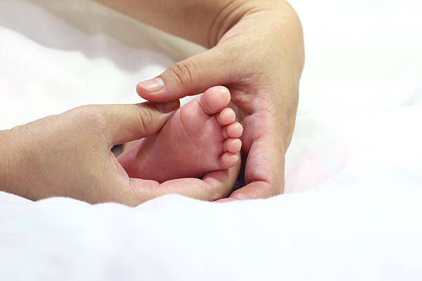 istock mom touch baby feet 491811594