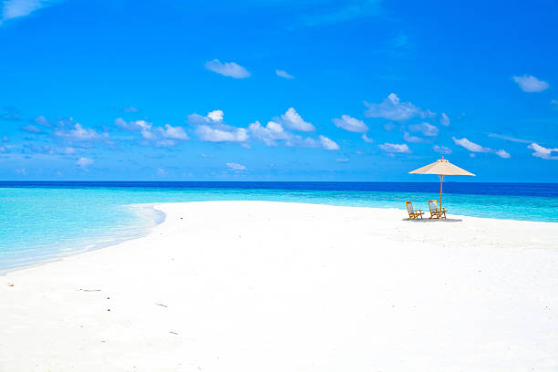 Maldives sandbank with umbrella and chairs Photo taken from a sandbank of an umbrella and two chairs, with the clear blue water in the background in the Maldives. sandbar stock pictures, royalty-free photos & images