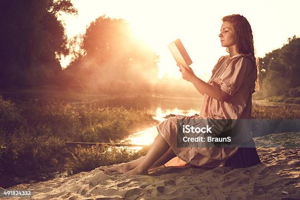 Book Reading Near The Pond At Sunset Stock Photo - Download Image Now - 2015, Adult, Adults Only