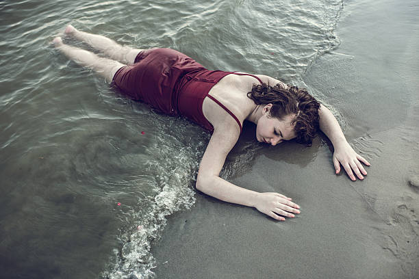 vista de arriba de inconsciente young woman lying en la playa. - ahogar fotografías e imágenes de stock