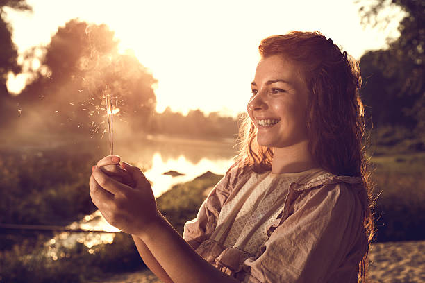 istock Happy redhead woman with a sparkler at sunset. 491826068