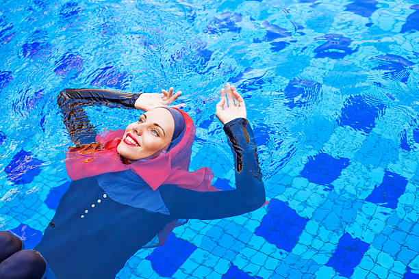 muslim caucasian woman swimming in a swimming pool muslim woman in red hijab swimming in a pool (lying on a back) vacation rental cleaning stock pictures, royalty-free photos & images