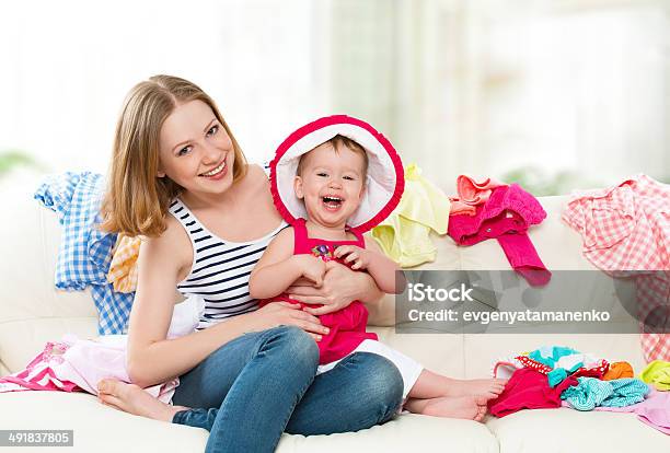 Happy Mother And Baby Girl With Clothes Ready For Traveling Stock Photo - Download Image Now