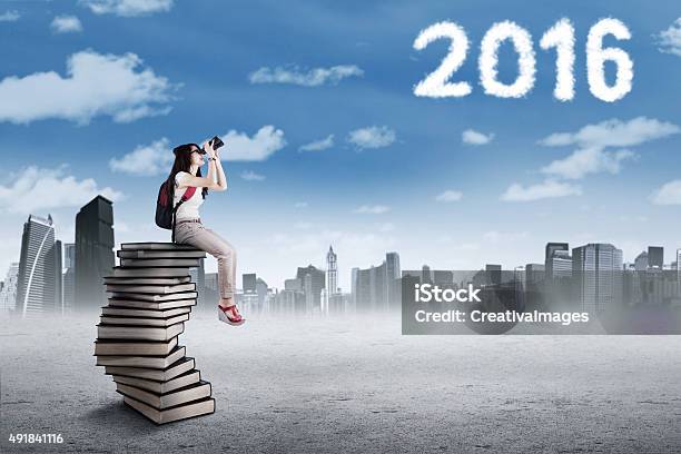 Student On The Pile Of Books Looking At Numbers 2016 Stock Photo - Download Image Now