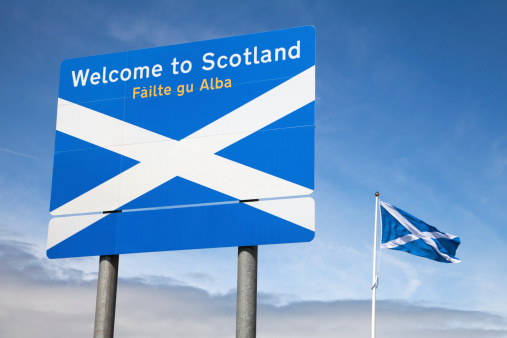 Welcome sign at the border between England and Scotland, with a Saltire (the national flag of Scotland) flying nearby.