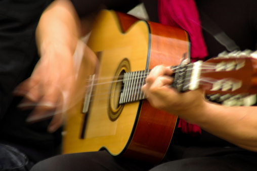Slow motion, blurred photo of a flamenco guitarist playing his guitar in the street. Granada, Andalucía, Spain.