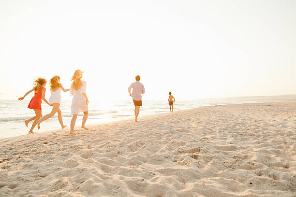 istock Group of friends runs on the beach at sunset 491853602