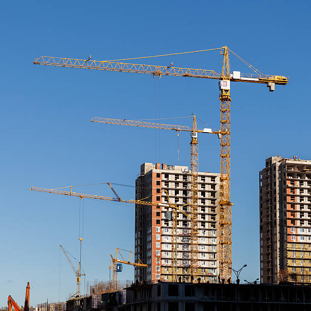 istock Construction cranes and built houses on blue sky background 491853846