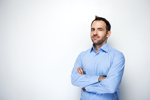 Portrait of a happy attractive business manager man wears blue shirt standing in hall of modern office building