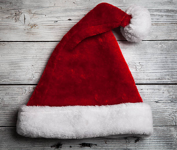 istock Santa Claus red hat on white rustic wooden background 491854282