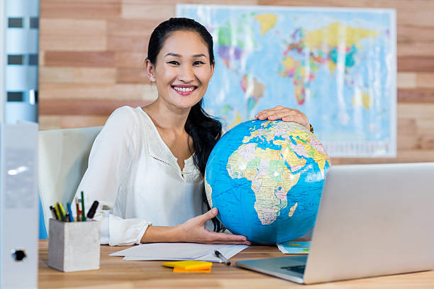 istock Pretty travel agent holding globe and smiling at camera 491855308