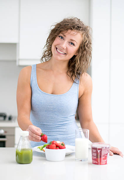 Woman eating a healthy breakfast at home and looking happy in the kitchen