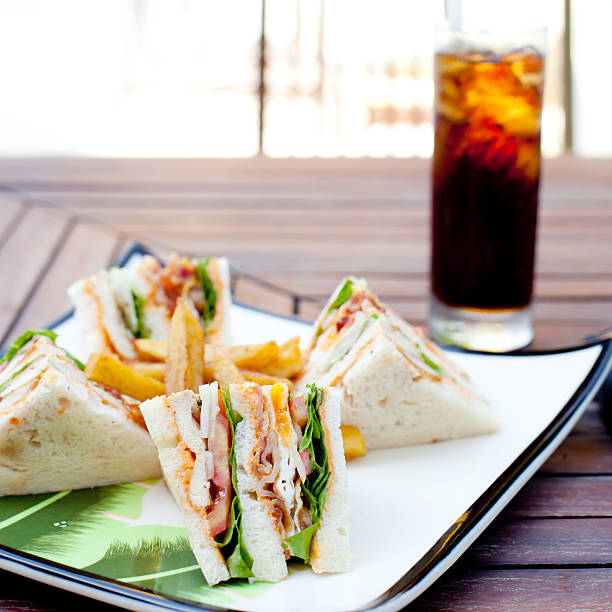 Club sandwich with iced soda drink on a wooden table. Fast food.