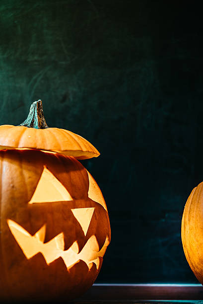istock halloween background with spooky illuminated pumpkin on blackboard 491858214