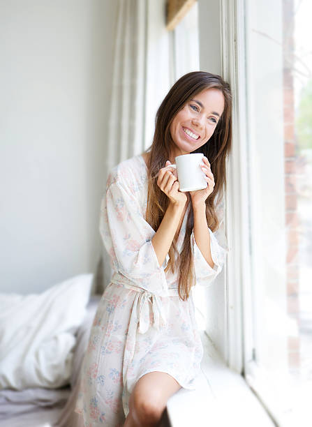 istock Woman sitting by window drinking tea 491870871
